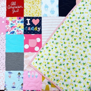 May include: A patchwork quilt with a variety of colorful fabrics, including floral patterns, stripes, and polka dots. The quilt is made up of squares and rectangles, and the back is a white fabric with a lemon pattern. The quilt has the text "All American Girl" and "I love daddy" on it.