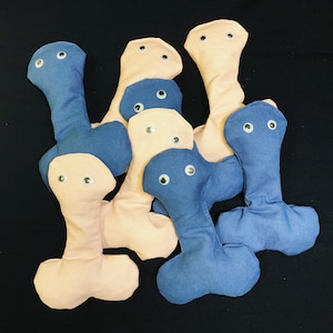 May include: A group of eight plush toys shaped like a human body. The toys are made of soft fabric and have button eyes. The toys are in various colors, including pink, blue, and white.
