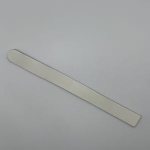 May include: A white nail file with rounded edges.