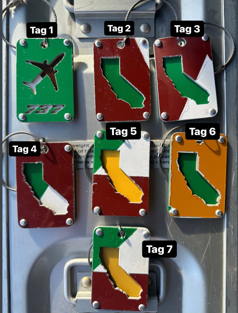 May include: Seven metal tags with different designs. The tags are all rectangular and have a green, white, red, orange, and yellow color scheme. The tags are labeled with the numbers 1 through 7. The tags are attached to a metal surface with a wire. The tags have the text '787' on one of them. The tags are all different sizes and shapes.