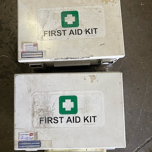 May include: Two white first aid kits with green crosses and the text "FIRST AID KIT" and "11NAS022-01".