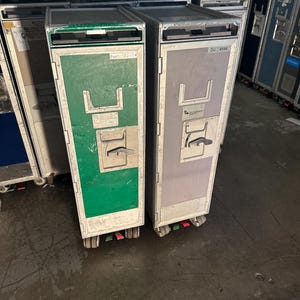 K&ouml;nnte beinhalten: Zwei Metall-Gep&auml;ckwagen mit R&auml;dern. Der Wagen links ist gr&uuml;n und hat den Text "22cm x 33.5cm" auf der Vorderseite. Der Wagen rechts ist grau und hat den Text "DU-4596" auf der Vorderseite.