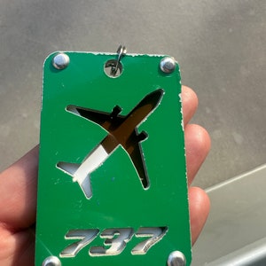 May include: A green metal keychain with a white airplane cutout and the number 737 in white lettering.