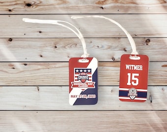 May include: Two luggage tags with red, white, and blue designs. The left tag has the text "ERIE PREMIER SPORTS MEMORIAL DAY CLASSIC MAY 27-29, 2023". The right tag has the text "WITMER 15 CENTURY".