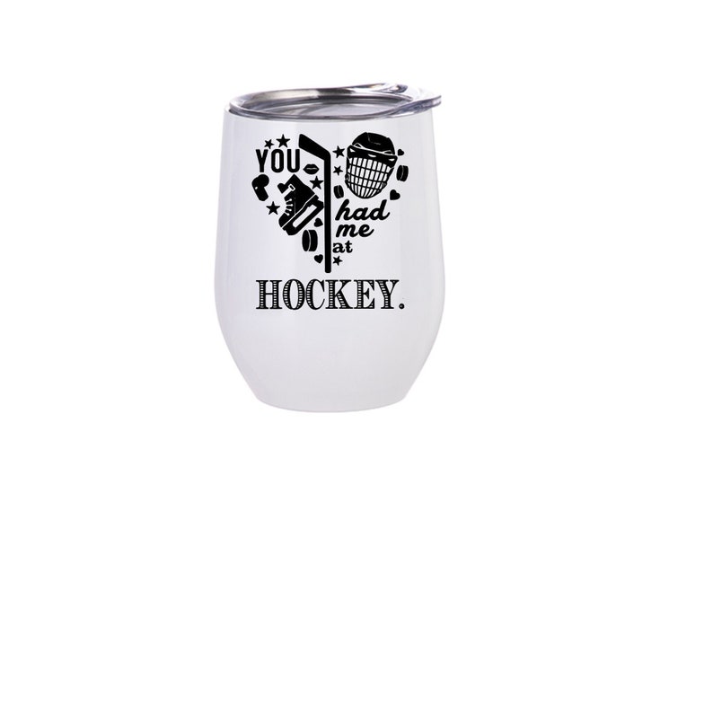 May include: White stainless steel wine tumbler with a black graphic that says "You had me at hockey." The graphic includes a hockey stick, puck, and other hockey equipment.