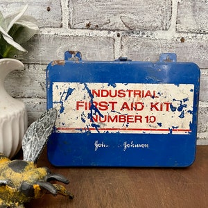 May include: Vintage blue metal first aid kit with white and red lettering that reads "INDUSTRIAL FIRST AID KIT NUMBER 10" and "John...Johnson".