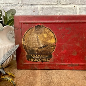May include: Vintage red metal tool chest with a yellow label that reads "Gilbert Big Boy Tool Chest".
