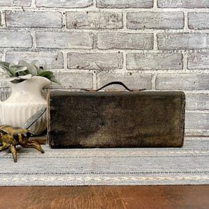 May include: A vintage, dark brown, rectangular suitcase with a leather handle. The suitcase is slightly worn and has a distressed look.