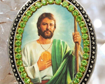 Op de afbeelding: Ovale hangerketting met een zilveren ketting en een groene en gouden afbeelding van een man met een baard en een groene robe. De hanger is omringd door een rand van groene strass.