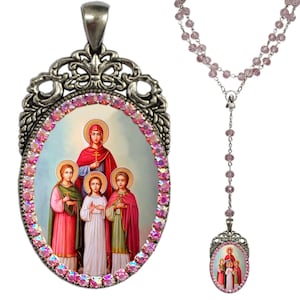 Può includere: Un ciondolo ovale d'argento con un bordo di cristallo rosa e un'immagine di un'icona religiosa. Il ciondolo è attaccato a una catena d'argento con perline di cristallo rosa.