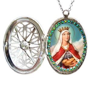 May include: Silver oval locket necklace with a green rhinestone border. The locket opens to reveal a picture of a woman wearing a crown and holding bread.