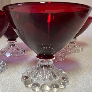 May include: Set of four ruby red glass dessert cups with clear glass stems and a beaded design.