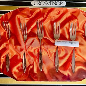 May include: Set of six silver cake forks in a red velvet lined box. The box has the words "Grosvenor Pacific" printed on it.