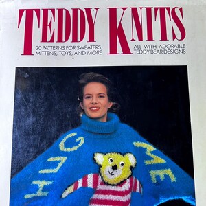 Peut inclure: Couverture du livre "TEDDY KNITS" avec une femme portant un pull bleu orné d'un ours en peluche et des mots "HUG ME". Le livre propose 20 patrons pour des pulls, des mitaines, des jouets et plus encore, avec des motifs d'ours en peluche.