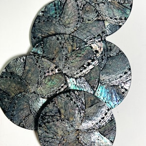 Peut inclure: Ensemble de dessous de verre ronds avec un motif en mosaïque. Les dessous de verre ont une surface gris foncé irisée avec un motif craquelé et des bords noirs. Les couleurs comprennent des nuances de gris, de vert et de bleu.