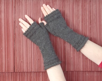 May include: A pair of gray fingerless gloves with a decorative stitch pattern. The gloves are made of a soft, fuzzy yarn.