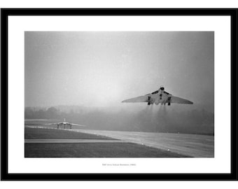 May include: A black and white photograph of a British Royal Air Force Avro Vulcan bomber taking off from a runway. The plane is in the air, with its landing gear retracted, and is leaving a trail of smoke behind it. There is another plane on the runway in the background.