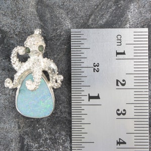 May include: Silver octopus pendant with a blue opal gemstone. The octopus has green eyes and is about 2 cm in size.