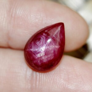 Puede incluir: Una piedra preciosa de rubí rojo en forma de lágrima con un patrón en forma de estrella.