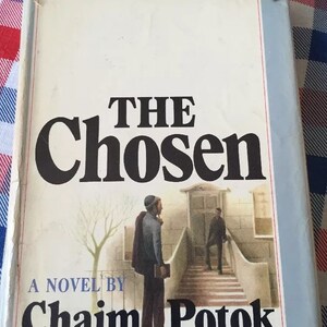 May include: A book cover with the title "THE Chosen" and the author's name "Chaim Potok". The cover features a black and white illustration of two men standing on a set of stairs.