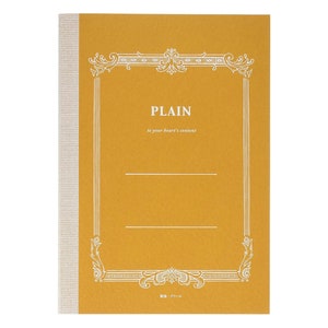 Op de afbeelding: Een geel notitieboek met een witte decoratieve rand en de tekst "PLAIN to your heart's content". Het notitieboek heeft een witte rug met een subtiel patroon.