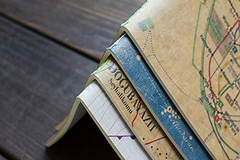 May include: Stack of four vintage notebooks with a map design on the cover. The top notebook has the text "Dogubayazit" and "Seyahatlikomu" printed on the spine.