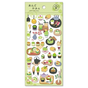 Puede incluir: Una hoja de pegatinas con varios postres y bebidas con temática de té verde. Las pegatinas están ilustradas en un estilo de dibujos animados e incluyen artículos como pastel de matcha, helado de té verde y lattes de matcha. La hoja está etiquetada como "And Cafe Seal" y presenta los caracteres japoneses para "té verde".