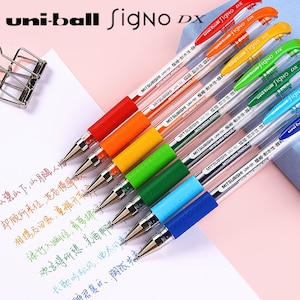 May include: A set of eight uni-ball Signo DX pens in various colours, including red, orange, yellow, green, blue, and black. The pens are all clear with a black ink cartridge and feature the text "uni-ball Signo DX" printed on the side.