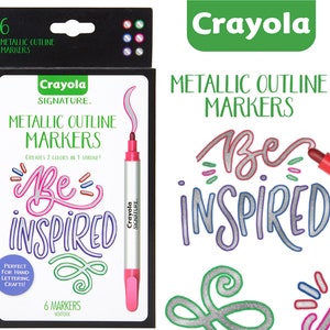 May include: A box of six Crayola Signature Metallic Outline Markers. The box is black with a white background and features a pink and silver marker with the text "Be Inspired" in silver and pink. The text "Crayola Signature" is also on the box. The box is surrounded by a white background.