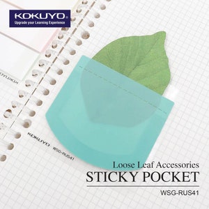 Puede incluir: Un bolsillo adhesivo transparente azul claro para carpetas de hojas sueltas. El bolsillo tiene forma de rectángulo curvo y una línea discontinua a lo largo del borde superior. El texto "WSG-RUS41" está impreso en la esquina inferior derecha del bolsillo. El texto "Loose Leaf Accessories STICKY POCKET WSG-RUS41" está impreso debajo del bolsillo.