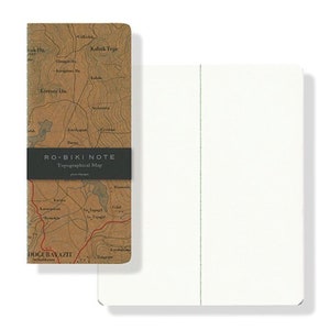 May include: A brown notebook with a topographical map on the front cover. The cover has the text "RO-BIKI NOTE Topographical Map" printed on it. The notebook is closed and the spine is visible. The notebook is on a white background.