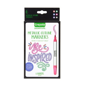 May include: A set of six Crayola Signature Metallic Outline Markers in a black and white box. The box features a pink marker with a silver metallic outline and the text "Be Inspired". The text "Creates 2 colors in 1 stroke!" is also on the box. The box is labeled "6 Markers Nontoxic".