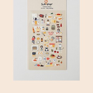 Pu&ograve; includere: Un foglio di adesivi con illustrazioni di cibo, elettrodomestici da cucina e persone che cucinano. Gli adesivi sono su uno sfondo beige e sono etichettati "Suatelier stickers no. 1117: vlog_cooking".