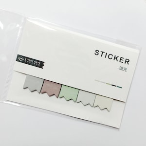 以下が含まれることがあります： 透明なプラスチック製のスリーブに入った付箋フラグのパッケージ。白いカードには黒で「STICKER」の文字が印刷され、その下に漢字が書かれています。グレー、モーヴ、グリーン、ライトグレー、オフホワイトの5色のパステルカラーのフラグが見えます。