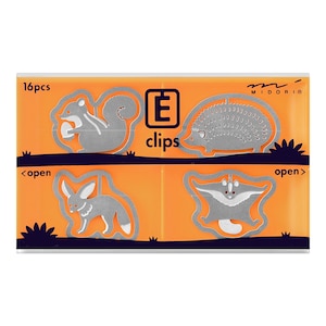 Puede incluir: Un juego de 16 clips de papel de metal plateado con forma de animales. Los clips están en un paquete de plástico transparente con fondo naranja. El paquete dice "E clips" y "MIDORI".
