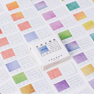 Puede incluir: Una hoja de pegatinas coloridas y estampadas con el texto "MON TUE WED THU FRI SAT SUN" y "1月2日" (2 de enero). Las pegatinas están diseñadas para usar en una agenda o diario.