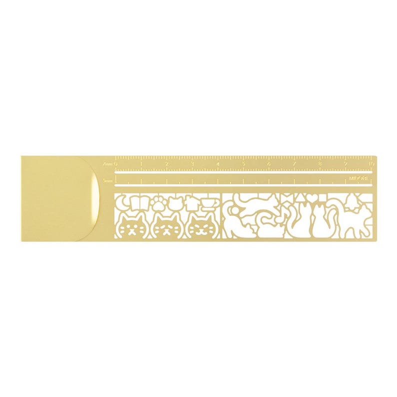May include: A gold-coloured metal ruler with cat-themed cut-out designs. The ruler has both centimetre and inch measurements. The cut-outs feature cat faces, paws, and other cat-related motifs. A stationery item.