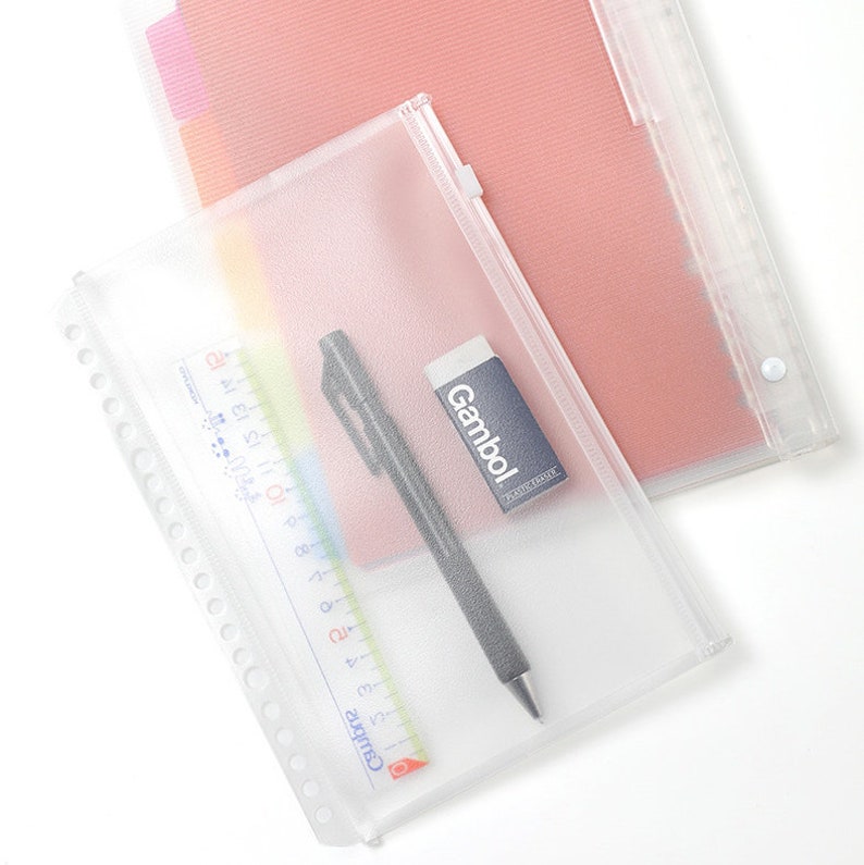 May include: A clear plastic zippered pouch with a black pen, a white eraser with the word "Gambol" printed on it, and a ruler with the word "Camiyu" printed on it.