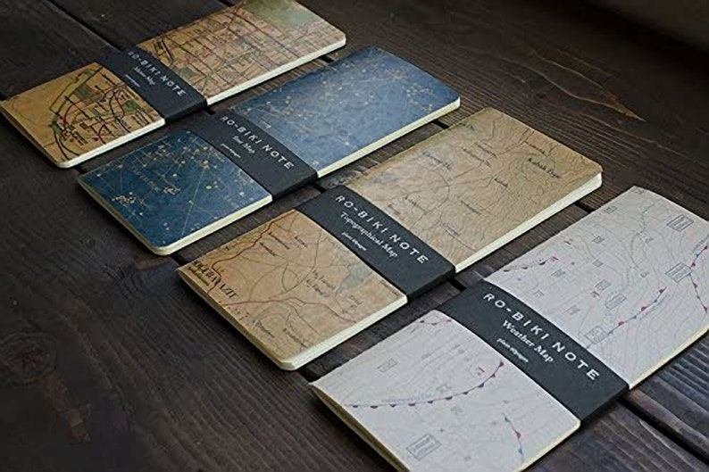 May include: Five different notebooks with black covers and map designs. The covers feature the text "RO-BIKI NOTE" and the type of map, such as "Topographical Map" or "Weather Map".