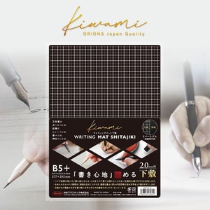 May include: A black and white writing mat with a grid pattern. The mat is labelled "Kiwami Writing Mat Shita Jiki" and is designed for use with pens, pencils, and other writing instruments. The mat is 277 mm by 202 mm and has a 2.0 mm grid.