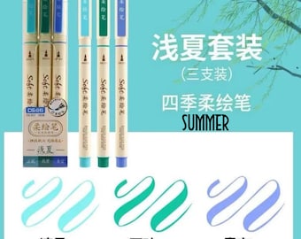 May include: A set of three summer-themed brush pens with light blue, green, and purple ink. The pens are labeled "Soft 柔绘笔" and "浅夏套装 (三支装) 四季柔绘笔 SUMMER". The ink colors are shown in a swirl pattern labeled "凉风", "万叶", and "青空".