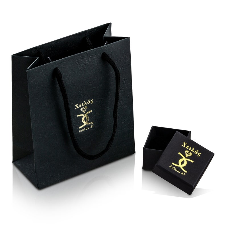 May include: Black gift bag with black handles and gold lettering that says "Xeil&aacute;s Aidonou 47". A smaller black box with gold lettering that says "Xeil&aacute;s Aidonou 47" is sitting in front of the bag.