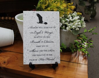 May include: A white stone plaque with black text and an eagle silhouette. The text reads "And He Will Raise You Up On Eagle's Wings, Bear You On The Breath Of Dawn, Make You To Shine Like The Sun, And Hold You In The Palm Of His Hand."