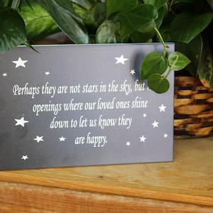 May include: A dark gray plaque with white stars and text. The text reads: "Perhaps they are not stars in the sky, but, openings where our loved ones shine down to let us know they are happy."