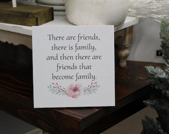 May include: White sign with a pink floral design and the text "There are friends, there is family, and then there are friends that become family."