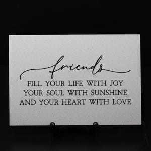 May include: A white sign with black text that reads "friends fill your life with joy your soul with sunshine and your heart with love".
