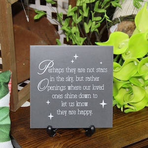 May include: A gray slate plaque with a white inscription that reads "Perhaps they are not stars in the sky, but rather openings where our loved ones shine down to let us know they are happy."
