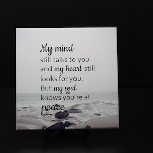 May include: A white ceramic tile with a black and white image of a beach and the text "My mind still talks to you and my heart still looks for you. But my soul knows you're at peace."