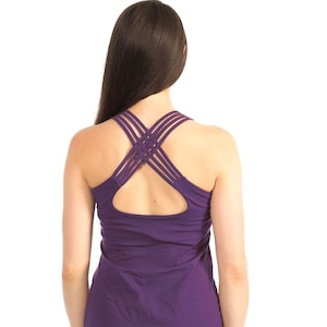 May include: Purple tank top with a criss-cross back design. The tank top is made of a soft, comfortable fabric and has a relaxed fit.