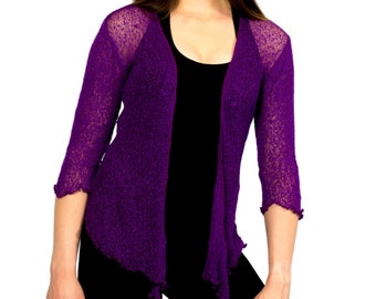 May include: A purple knitted cardigan with a slightly open front and a ruffled hem. The cardigan is made of a lightweight, airy fabric.